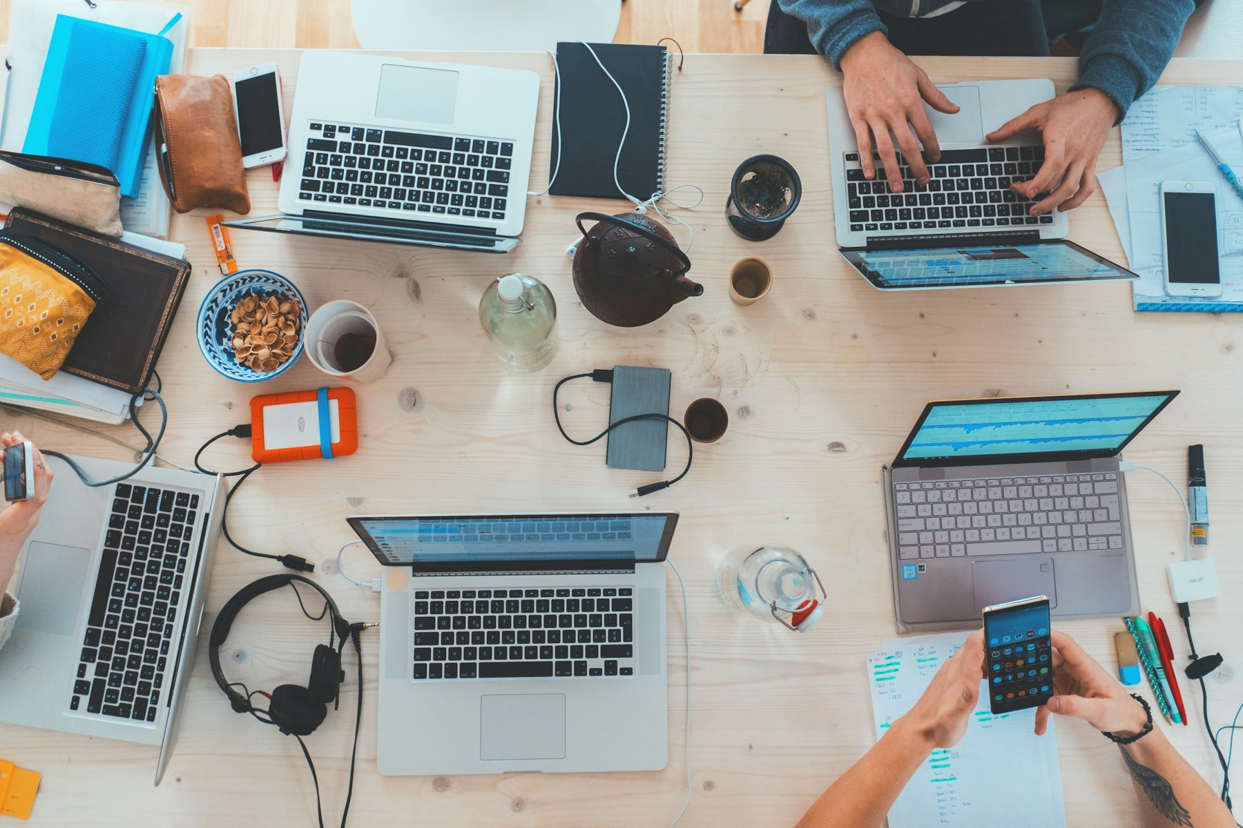 Des ordinateurs et des mains autour d’une table