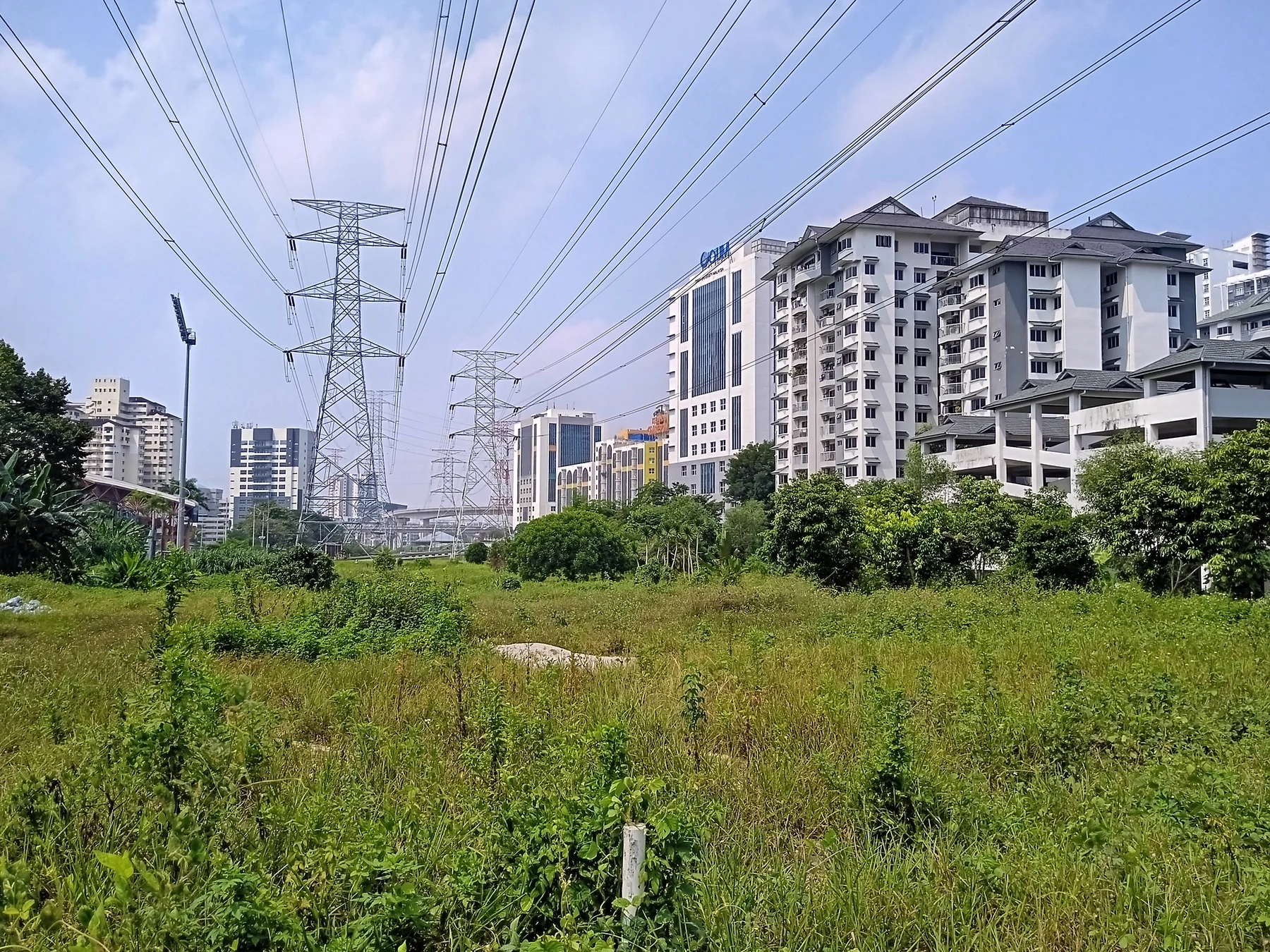 Des lignes à haute tension traversent un quartier de Petaling Jaya, en Malaisie, au-dessus d’un corridor végétalisé.