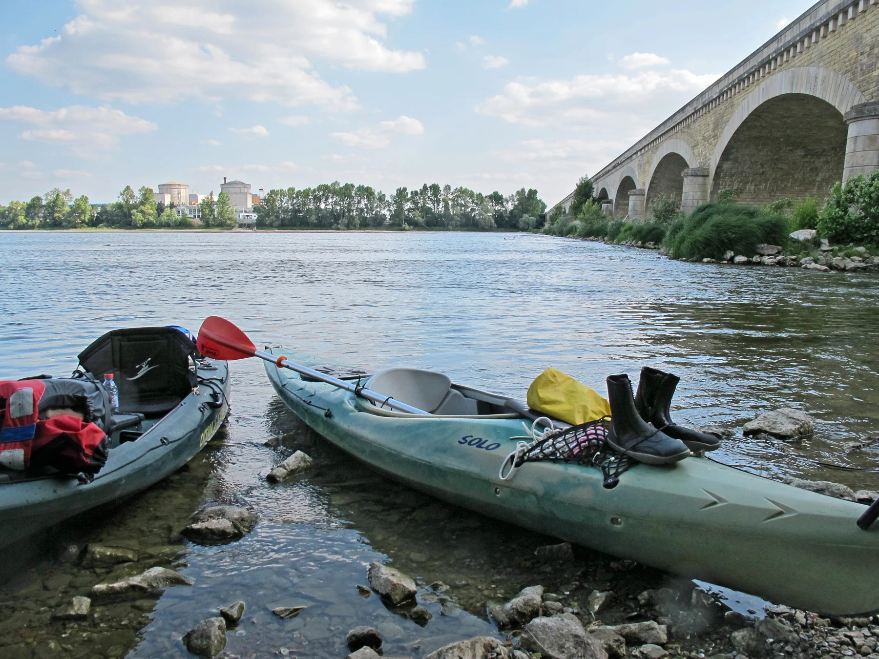 La Loire, des kayaks au premier plan, un pont et la centrale de Chinon à l’horizon.