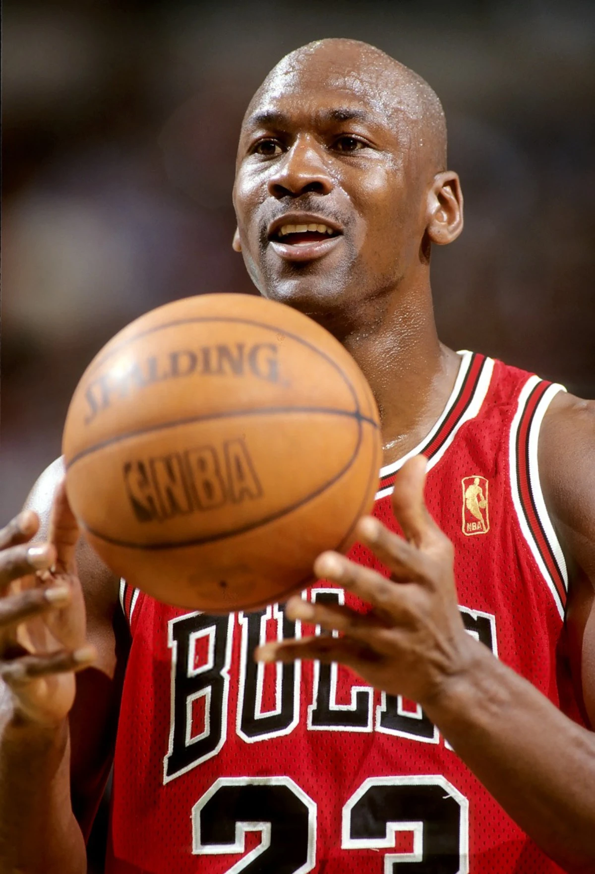 Michael Jordan tenant un ballon de basketball devant lui, avec une tenue rouge des Bulls.