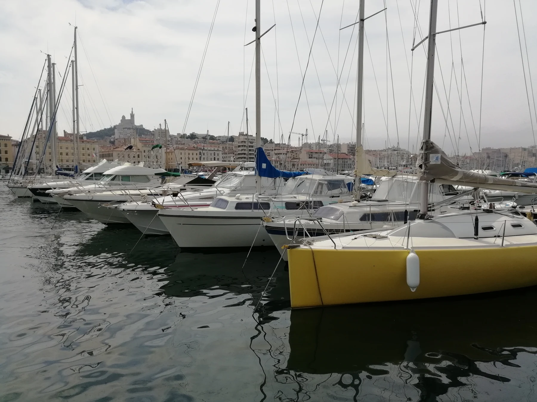Bateaux amarrés dans le Vieux-Port de Marseille, avec la ville à l’arrière-plan.